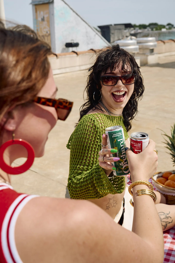 two friends sharing orchard cans on a rooftop