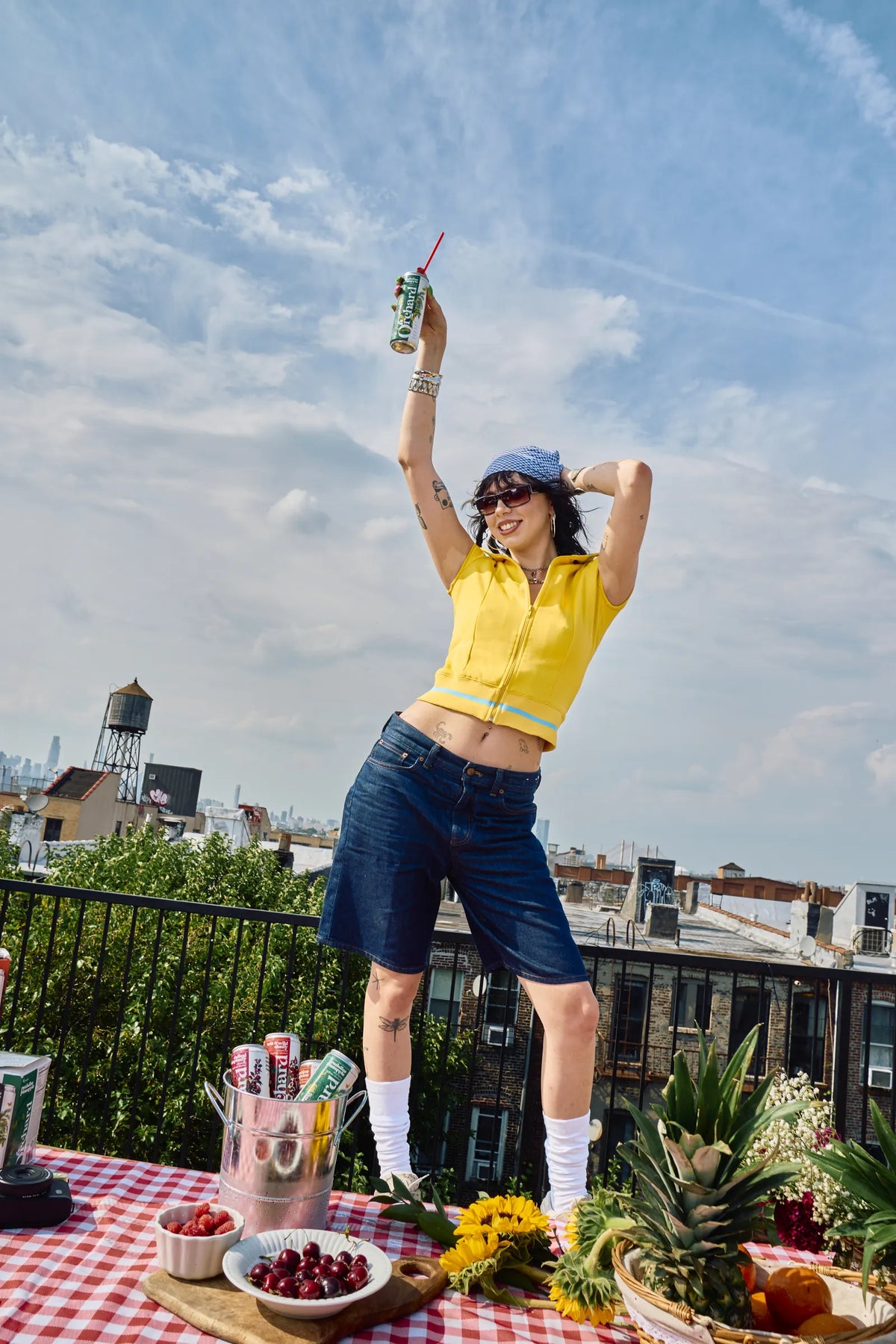 woman in yellow raising an Orchard can to the sky
